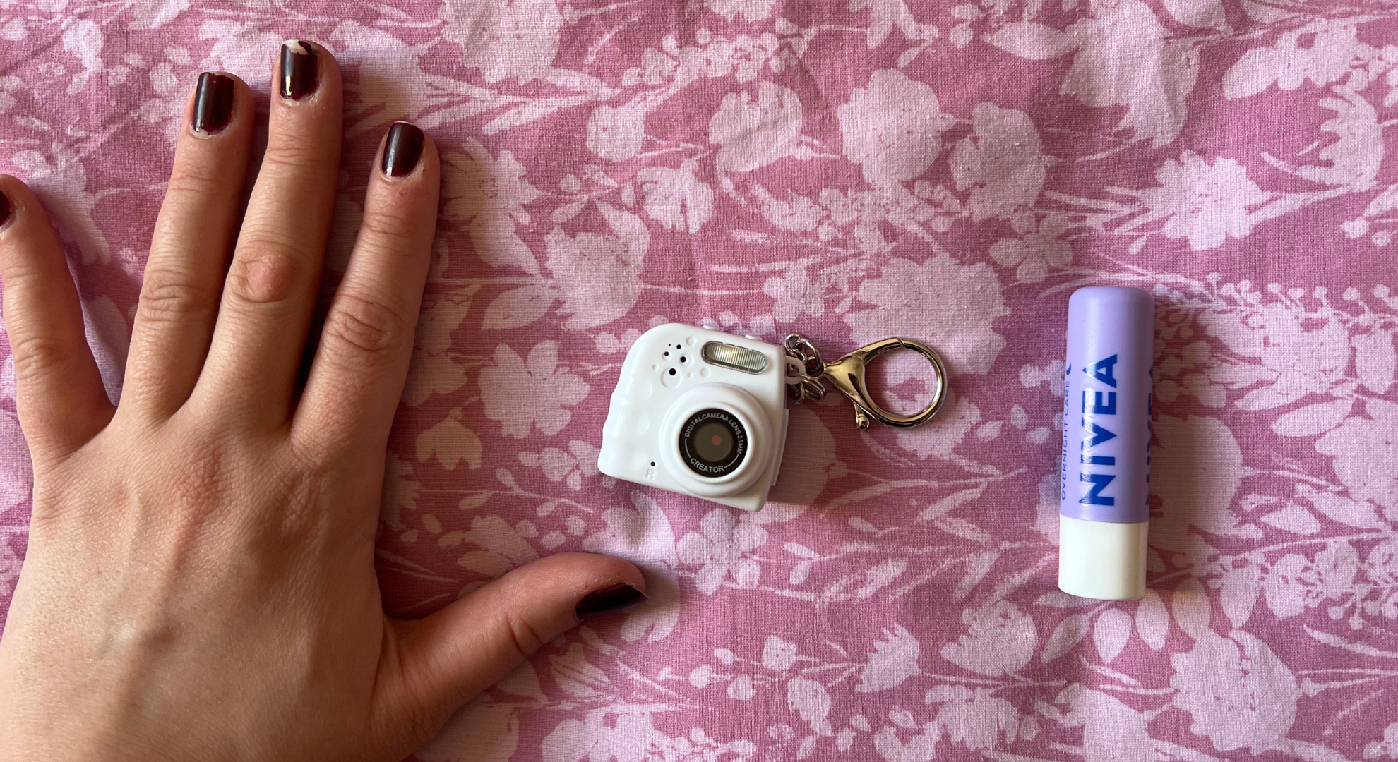 Photo Creator Mini Cam Digital Camera from Canal Toys next to a hand and a chapstick for size reference.